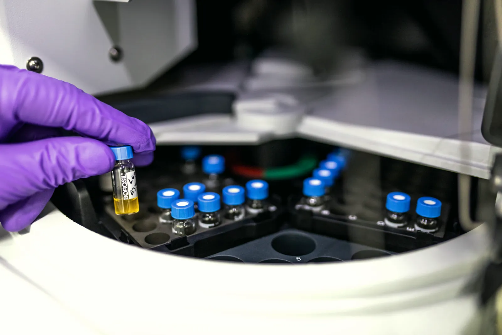 Analyst loading ingredient samples into an HPLC autosampler for batch testing in the ModernVEDA laboratory